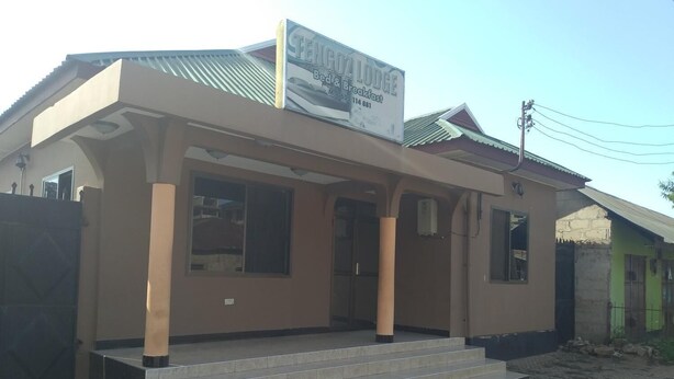 A building with a sign for "Fengoz Lodge Bed & Breakfast" and a small porch with steps leading to the entrance. - Tengoz Lodge (Morogoro)