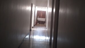 A long, narrow hallway with a tiled floor and white walls. - Tengoz Lodge (Morogoro)