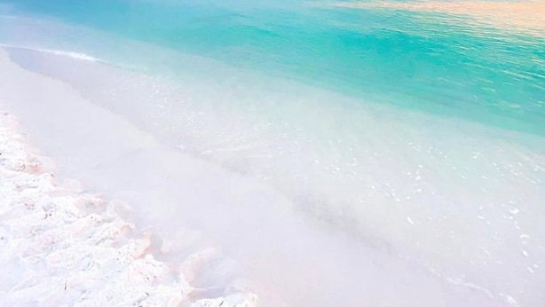 Uma praia com águas turquesa cristalinas e areia branca.