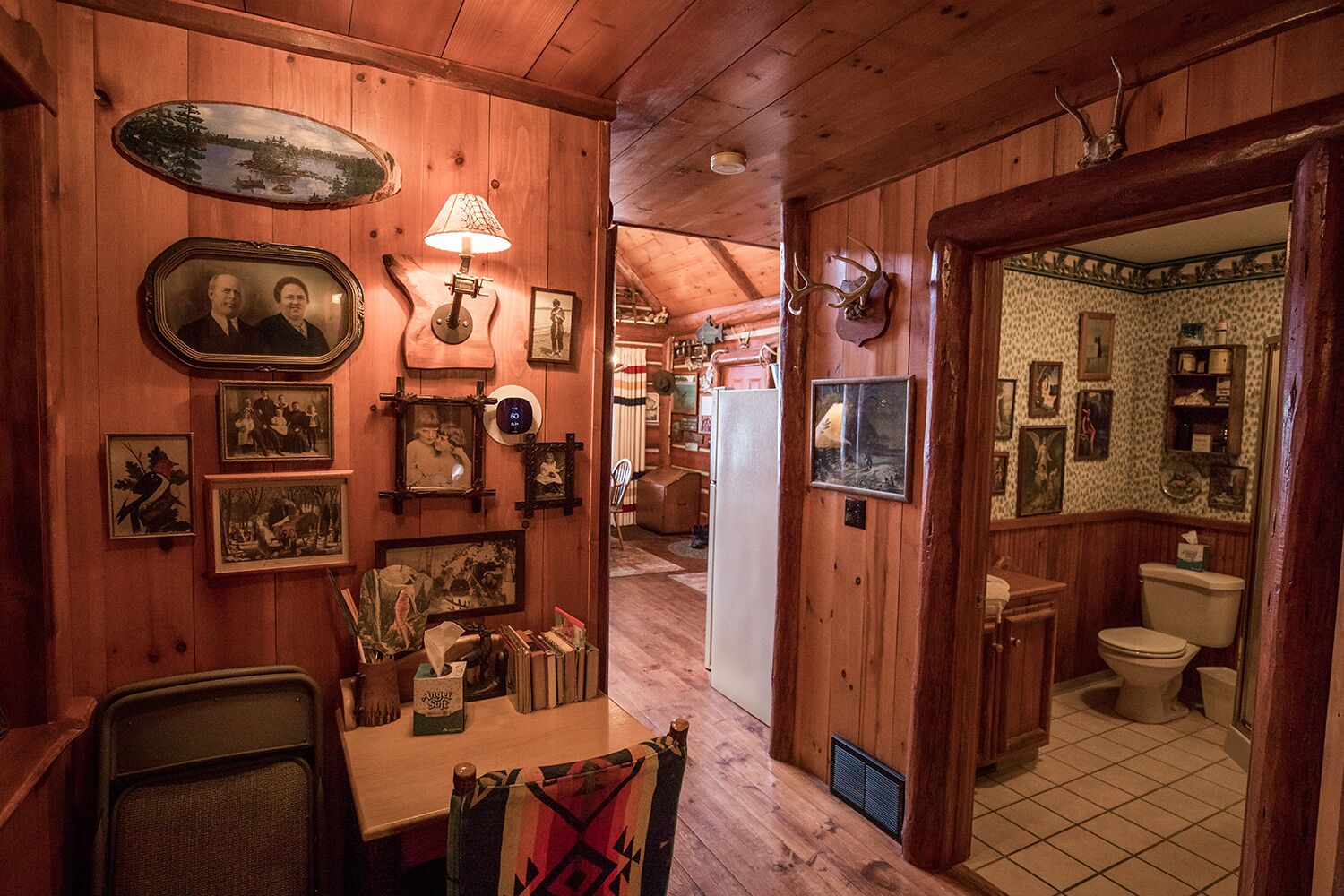 A wooden cabin interior with a dining area, kitchen, and bathroom.