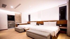 A modern hotel room with two beds, a small seating area, and a stone wall. - Beauty Avenue Inn (Kaohsiung)