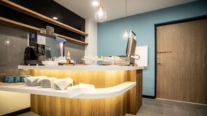 A reception area with a curved counter, a coffee machine, and a digital display. - Beauty Avenue Inn (Kaohsiung)