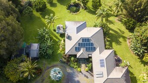 A large house with multiple solar panels on the roof, surrounded by lush greenery and a well-maintained lawn. - Amazing VIEWS, Spacious, Farmstead Living, Hosts with Aloha (Hawi)