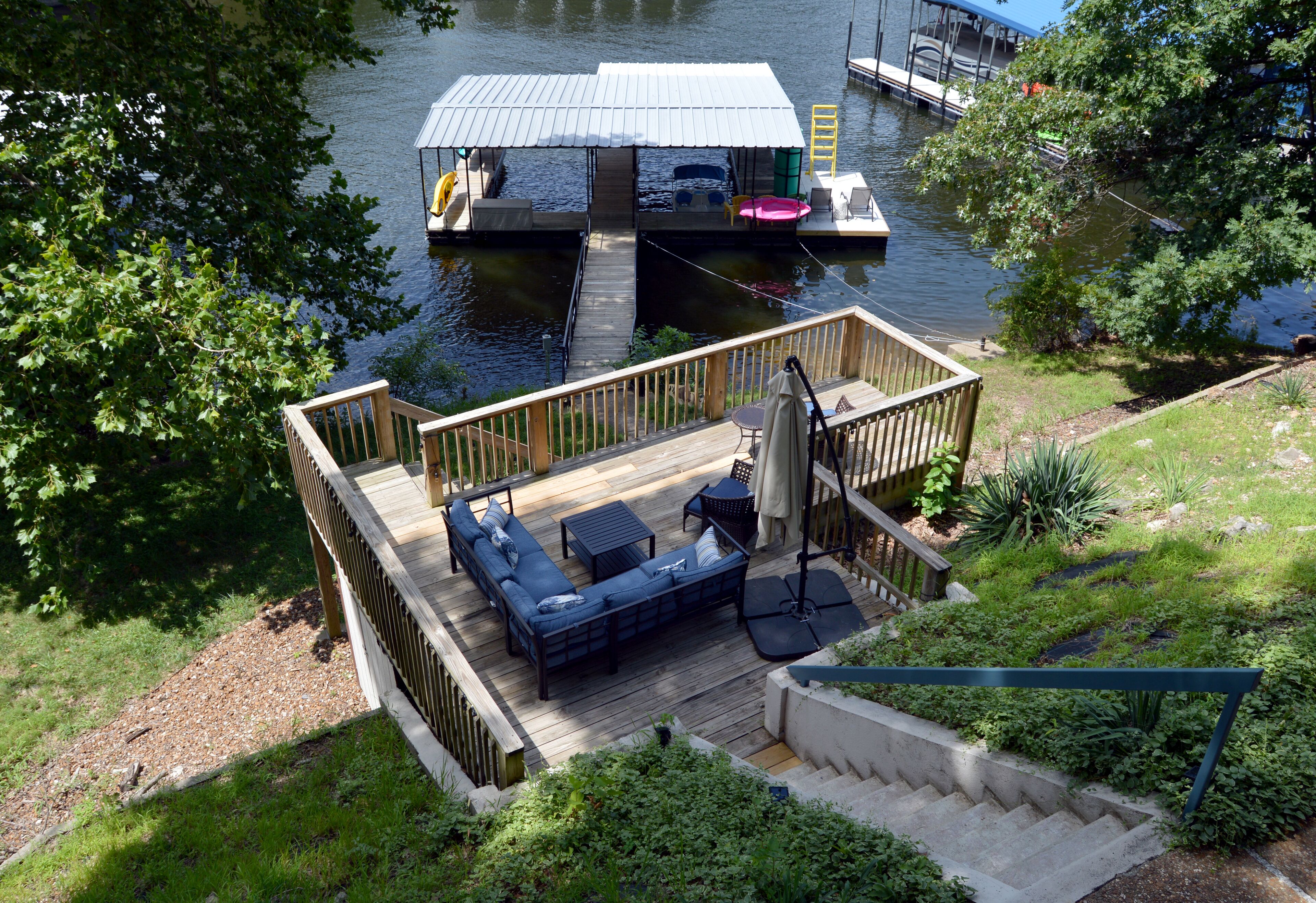 Eine Terrasse mit Sitzgelegenheiten im Freien, ein überdachter Bereich und ein Steg, der ins Wasser führt.