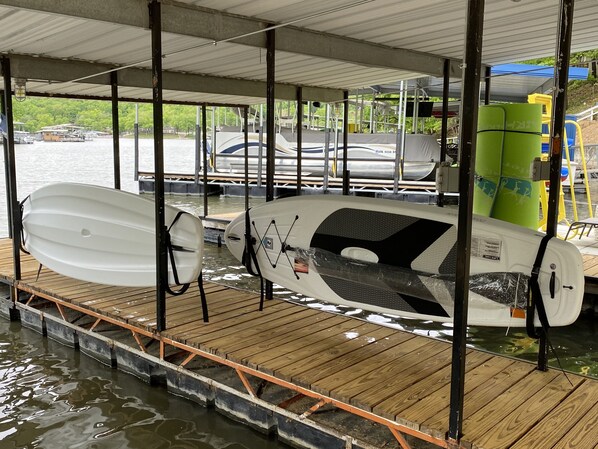 Un muelle techado con varias embarcaciones y kayaks asegurados en estantes.
