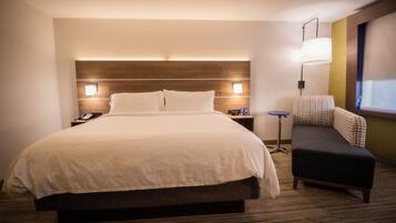 Una habitación de hotel con una cama grande, lámparas de noche, una mesita, una silla y una ventana.