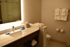 A bathroom with a sink, mirror, towel rack, toilet, and patterned wall tiles. - Holiday Inn Express & Suites Boston South - Randolph by IHG (Randolph)