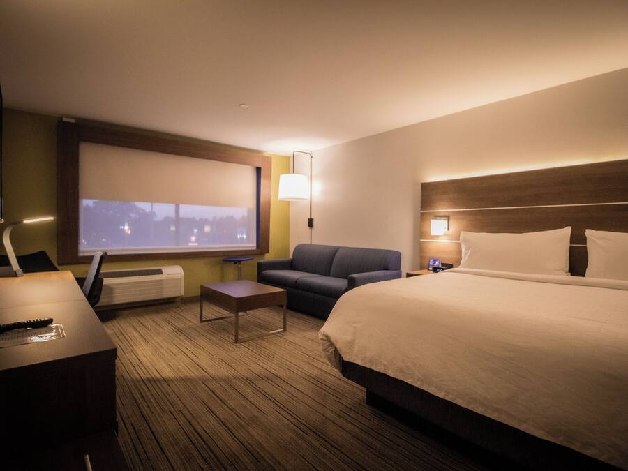 Una habitación de hotel con cama, sofá, televisor y escritorio.