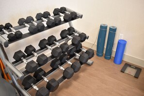 A gym with a rack of dumbbells, yoga mats, and a scale. - Holiday Inn Express & Suites Boston South - Randolph by IHG (Randolph)