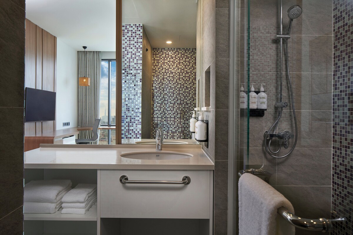 Een moderne badkamer met een douche in een glazen cabine, een wastafelmeubel met een wastafel en een handdoekrek.