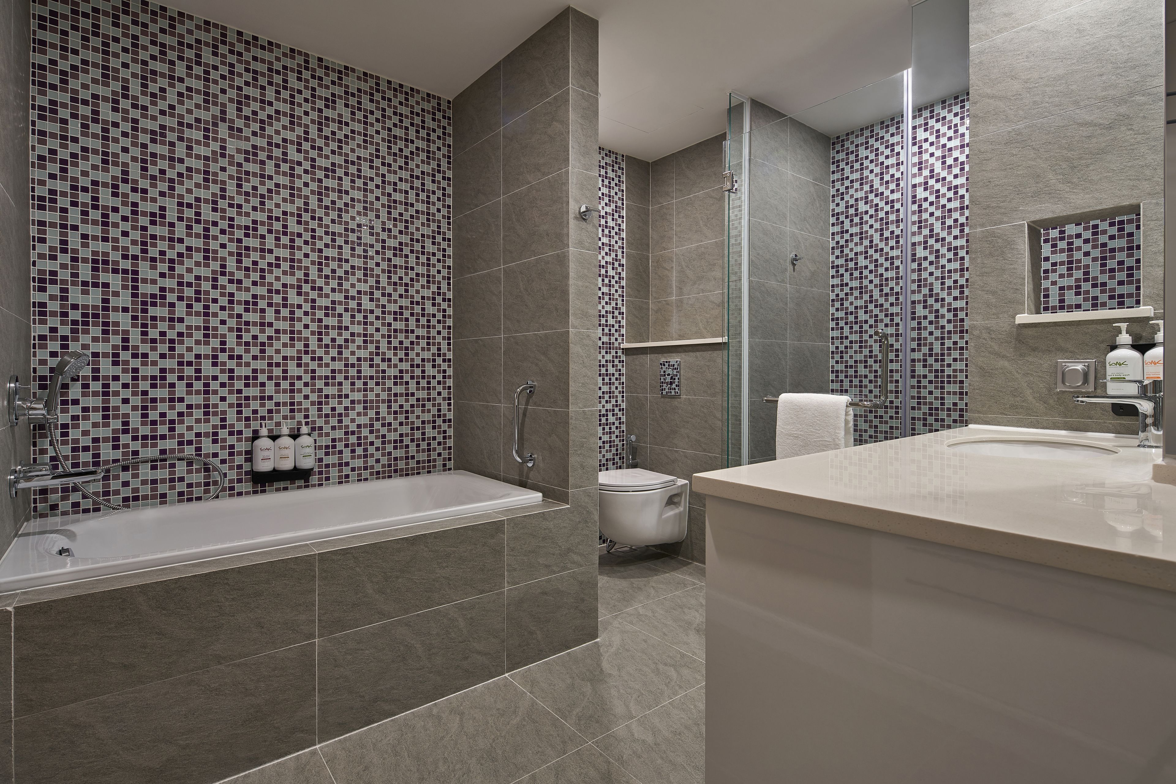 Ein modernes Badezimmer mit einer großen Badewanne, einer Dusche und einem Waschtisch mit Spiegel.