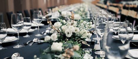Una larga mesa de comedor decorada con flores blancas y cristalería transparente, presumiblemente en un ambiente formal.