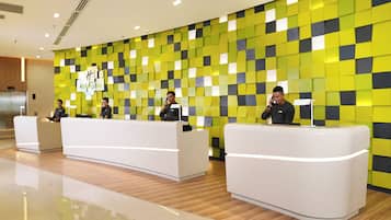 A hotel reception area with a modern design, featuring a check-in counter and a reception desk.