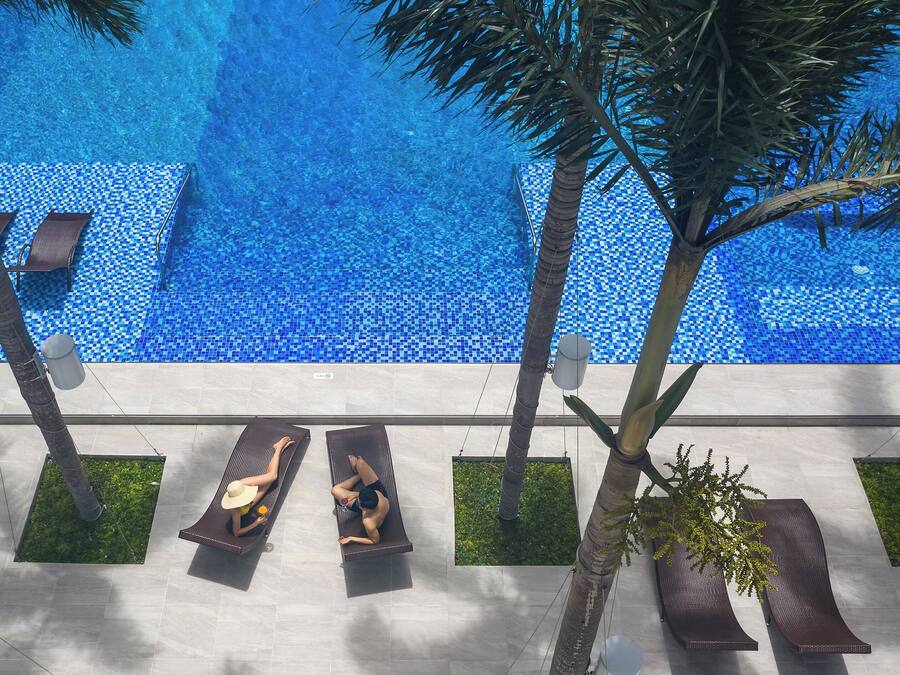 A pool area with lounge chairs and palm trees.