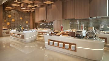 A modern buffet setup with multiple serving stations, a tiled backsplash, and contemporary lighting fixtures.