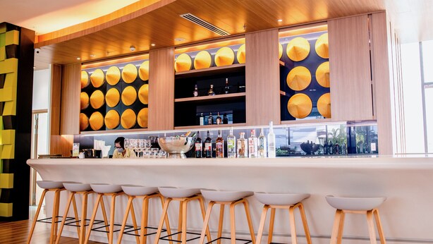 Een barruimte met houten krukken, een bar en flessenkasten.