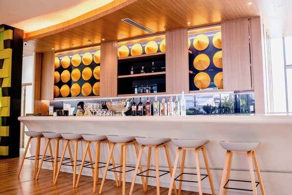 Een barruimte met houten krukken, een bar en flessenkasten.