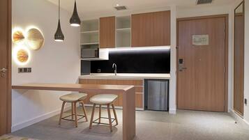 Una cocina moderna con una isla central, taburetes de bar, iluminación colgante y un microondas.