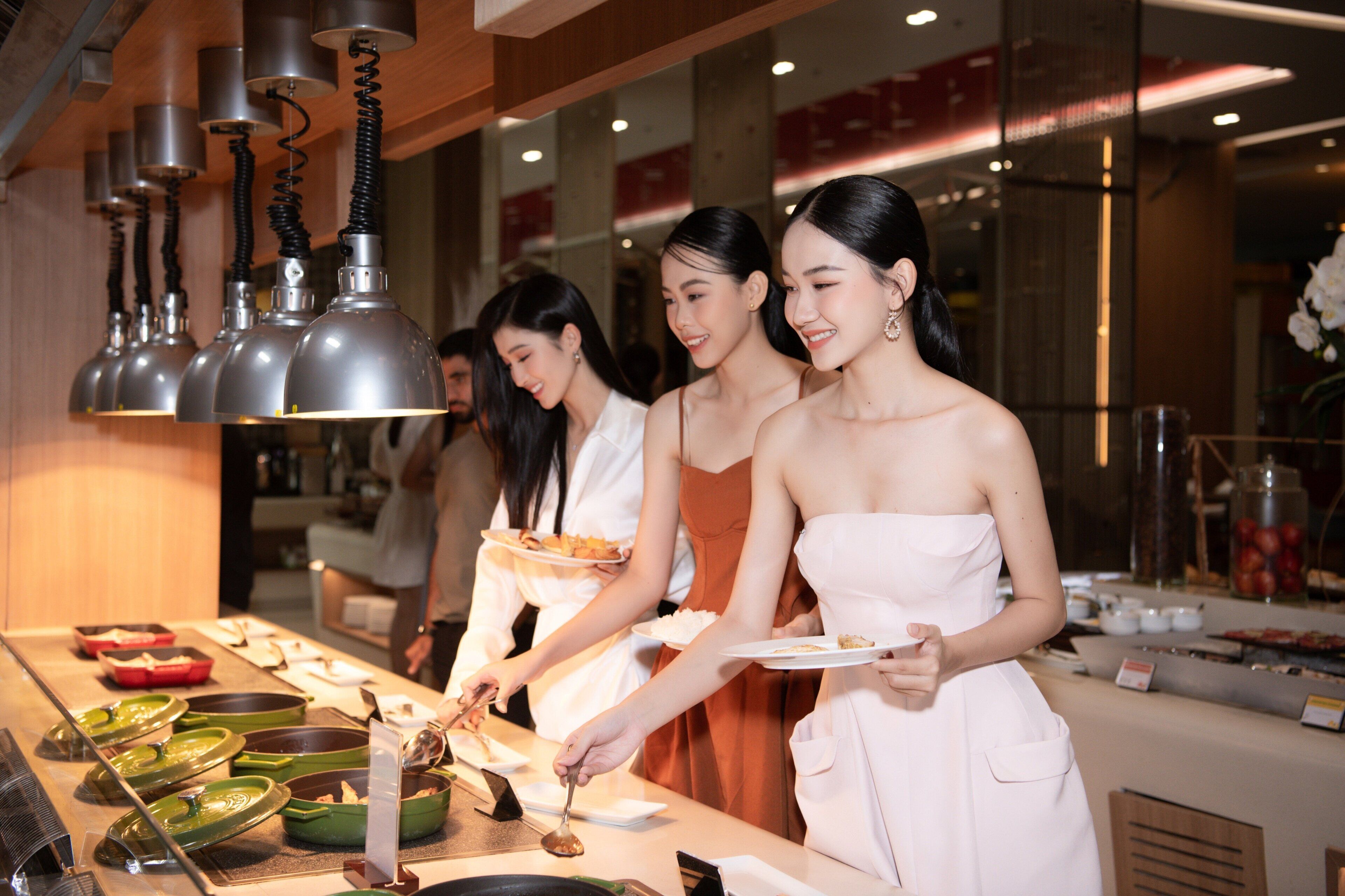 A group of individuals serving food at a buffet with various dishes and utensils on display.