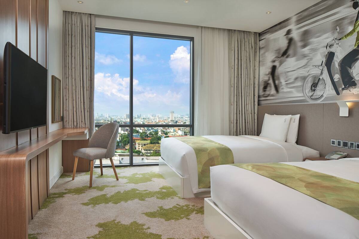 Une chambre d’hôtel avec une grande fenêtre, un lit, un bureau et une chaise.