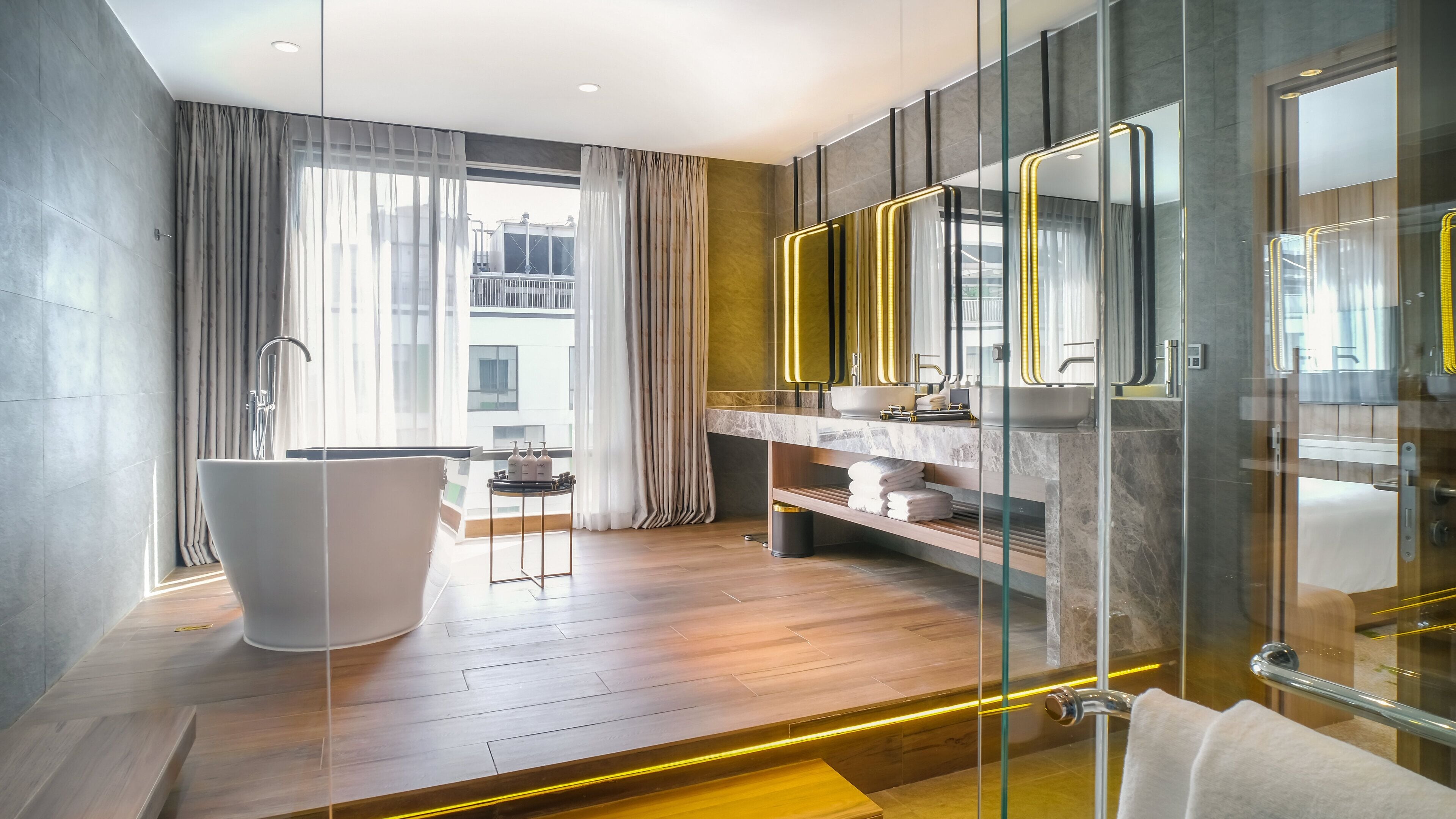 A modern bathroom with a freestanding bathtub, a glass-enclosed shower, and a vanity with a marble countertop.
