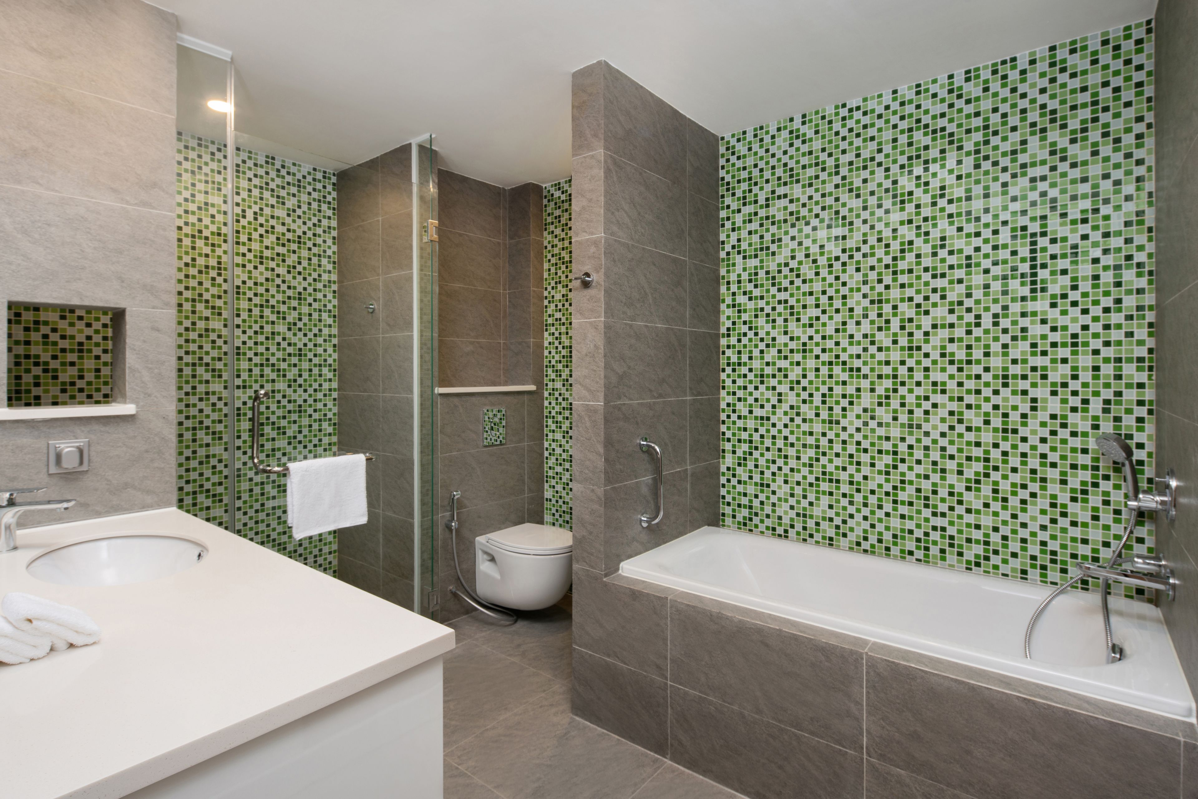 A modern bathroom with a glass-enclosed shower, a white bathtub, and a sink with a mirror.