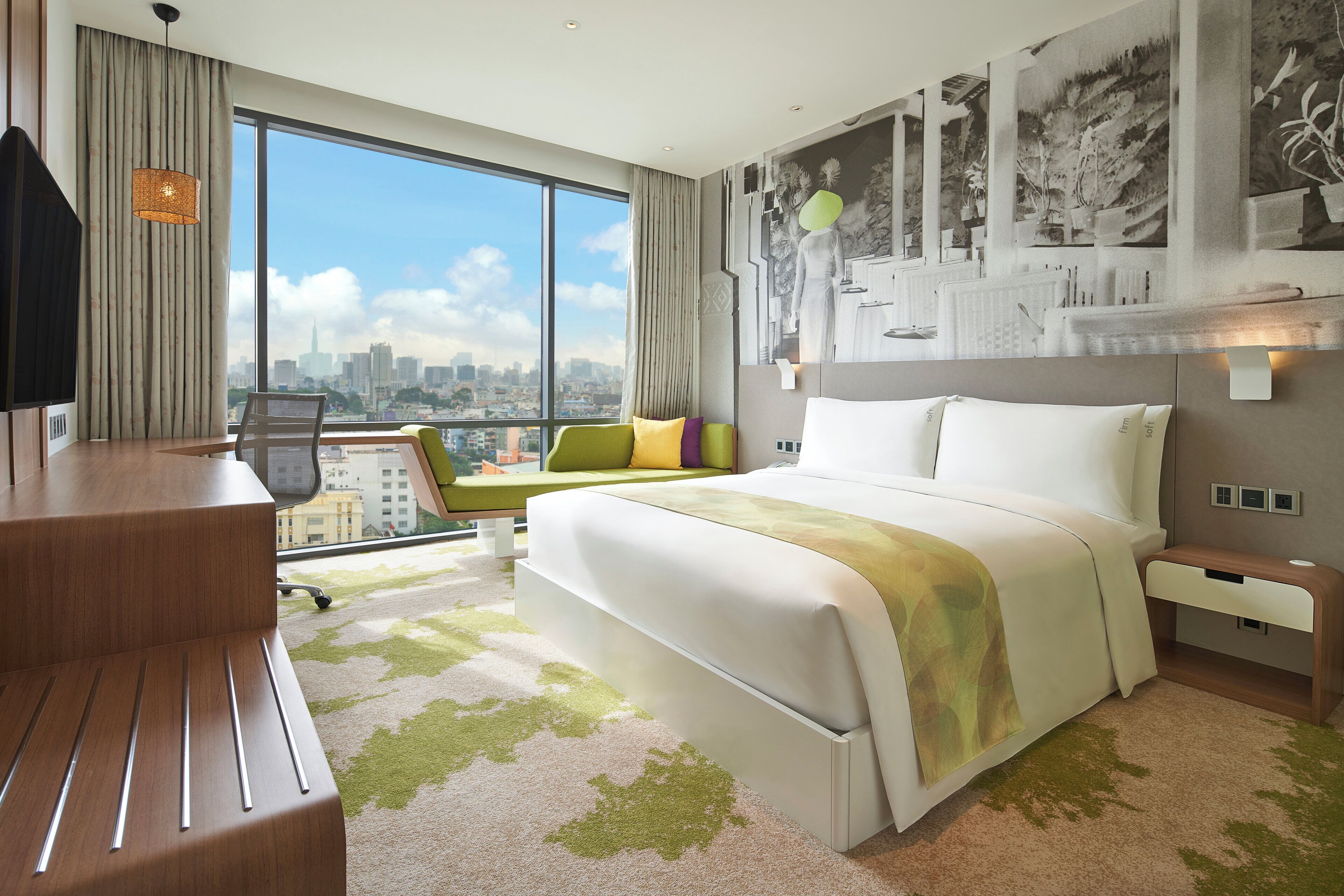 Habitación de hotel con una cama grande, un escritorio, una silla y vistas a la ciudad.