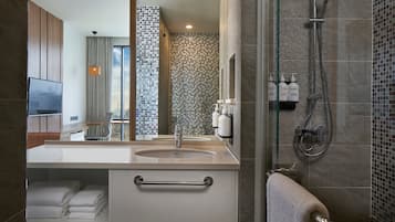 A modern bathroom with a large sink, a glass shower enclosure, and a tiled shower wall.
