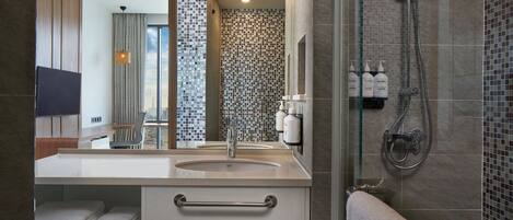 A modern bathroom with a glass shower enclosure, a sink with a towel rack, and a mirror.