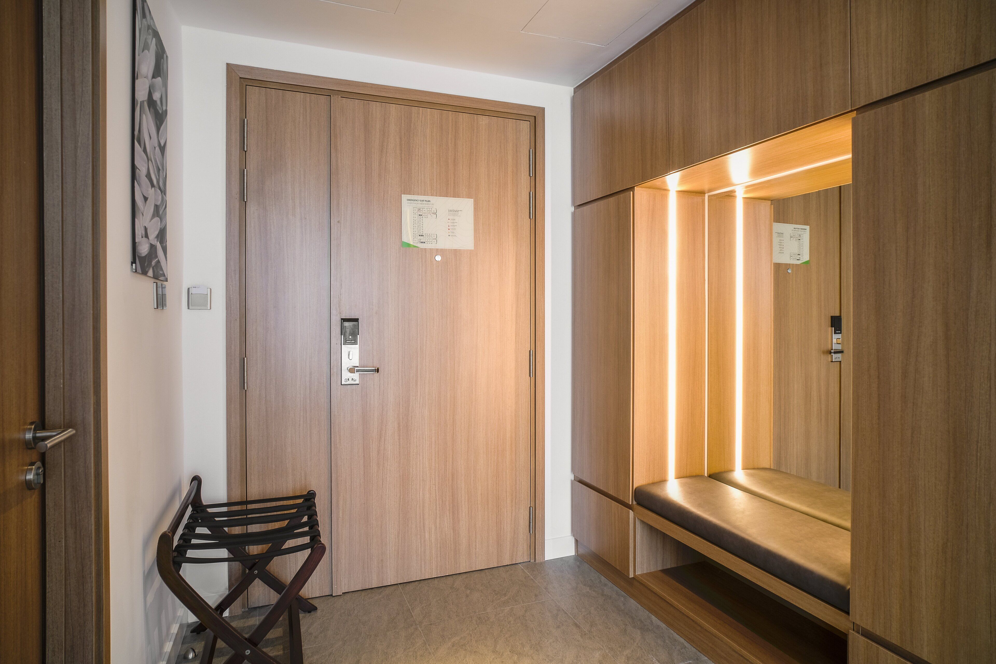 Une chambre d’hôtel avec une armoire en bois, un banc et un miroir fixé au mur.