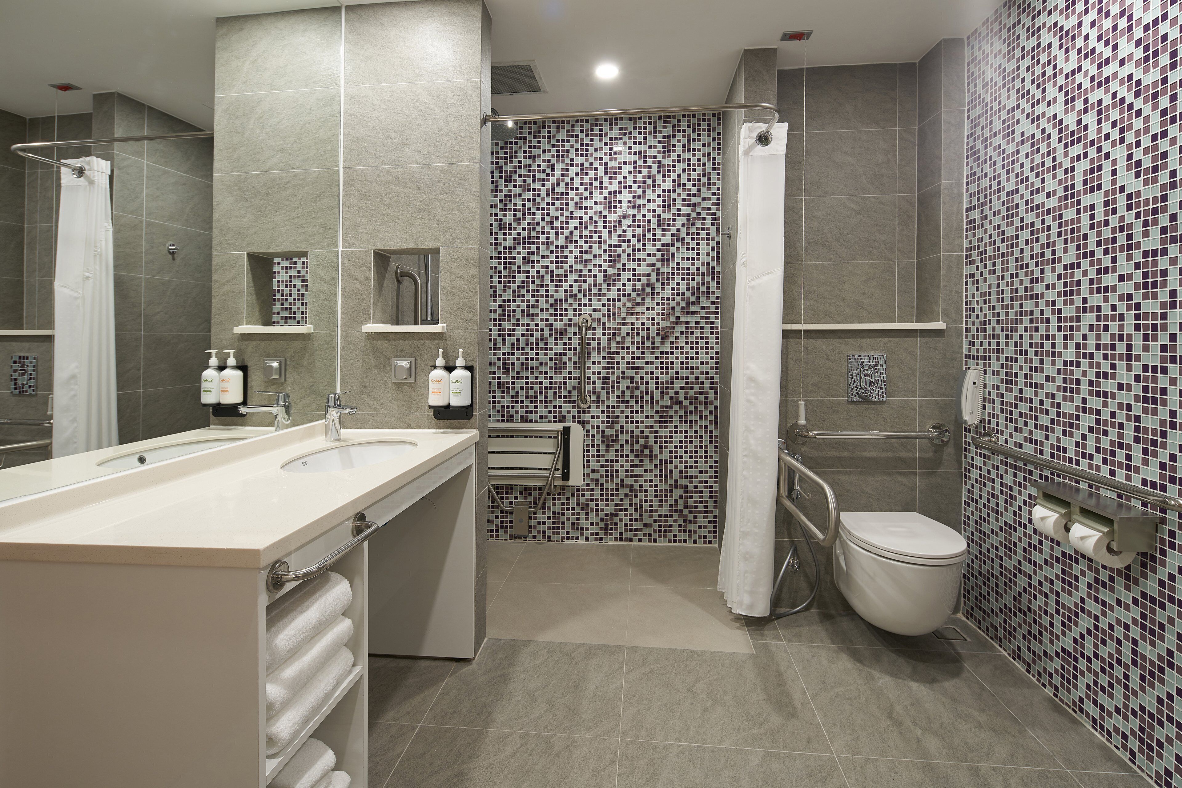 A modern bathroom with a shower, toilet, and two sinks.
