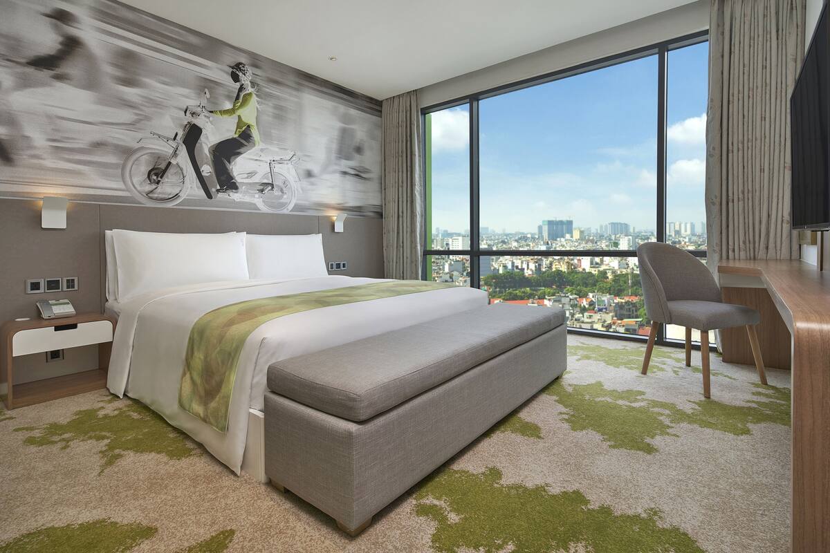 Une chambre d’hôtel moderne avec un grand lit, une vue sur la ville, un bureau et une chaise.
