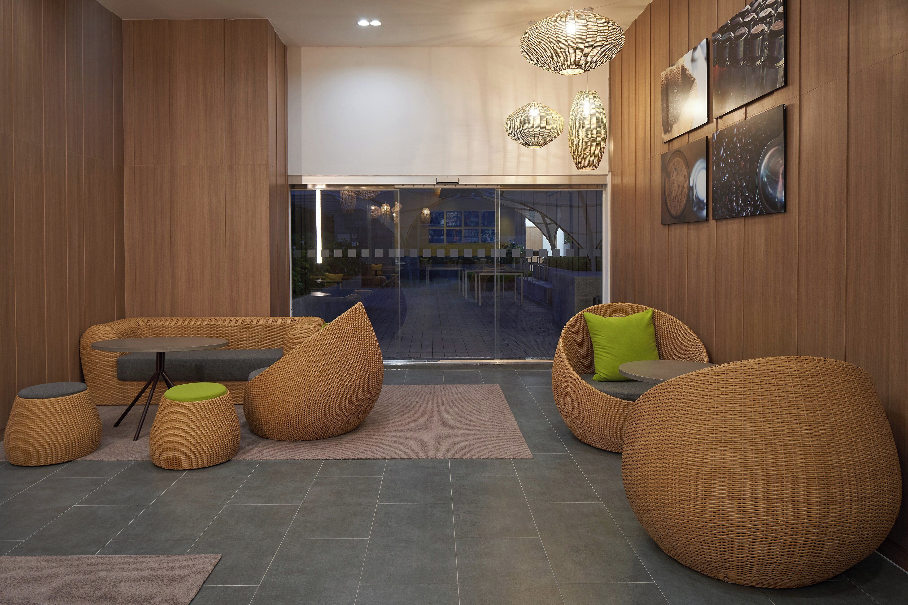 Een modern interieur met rieten meubels, een glazen deur naar buiten en houten lambrisering.