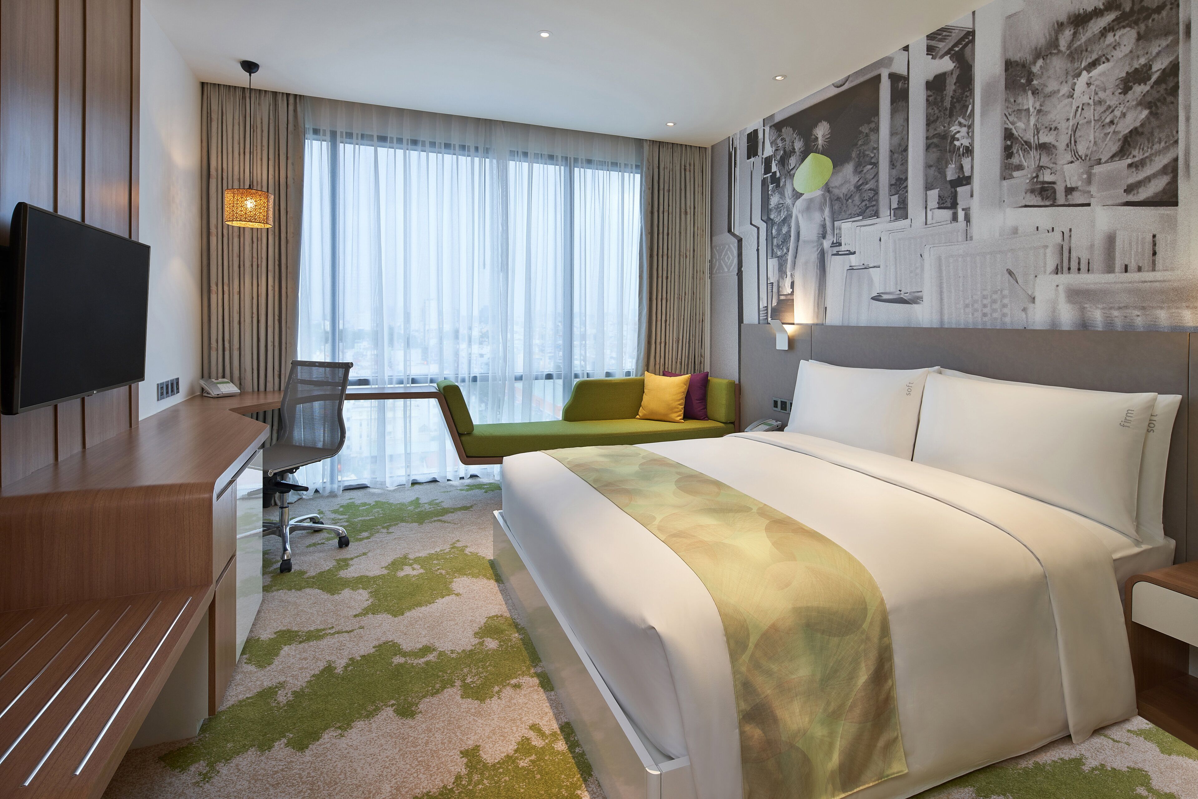 A modern hotel room with a large bed, a desk, a chair, and a television.