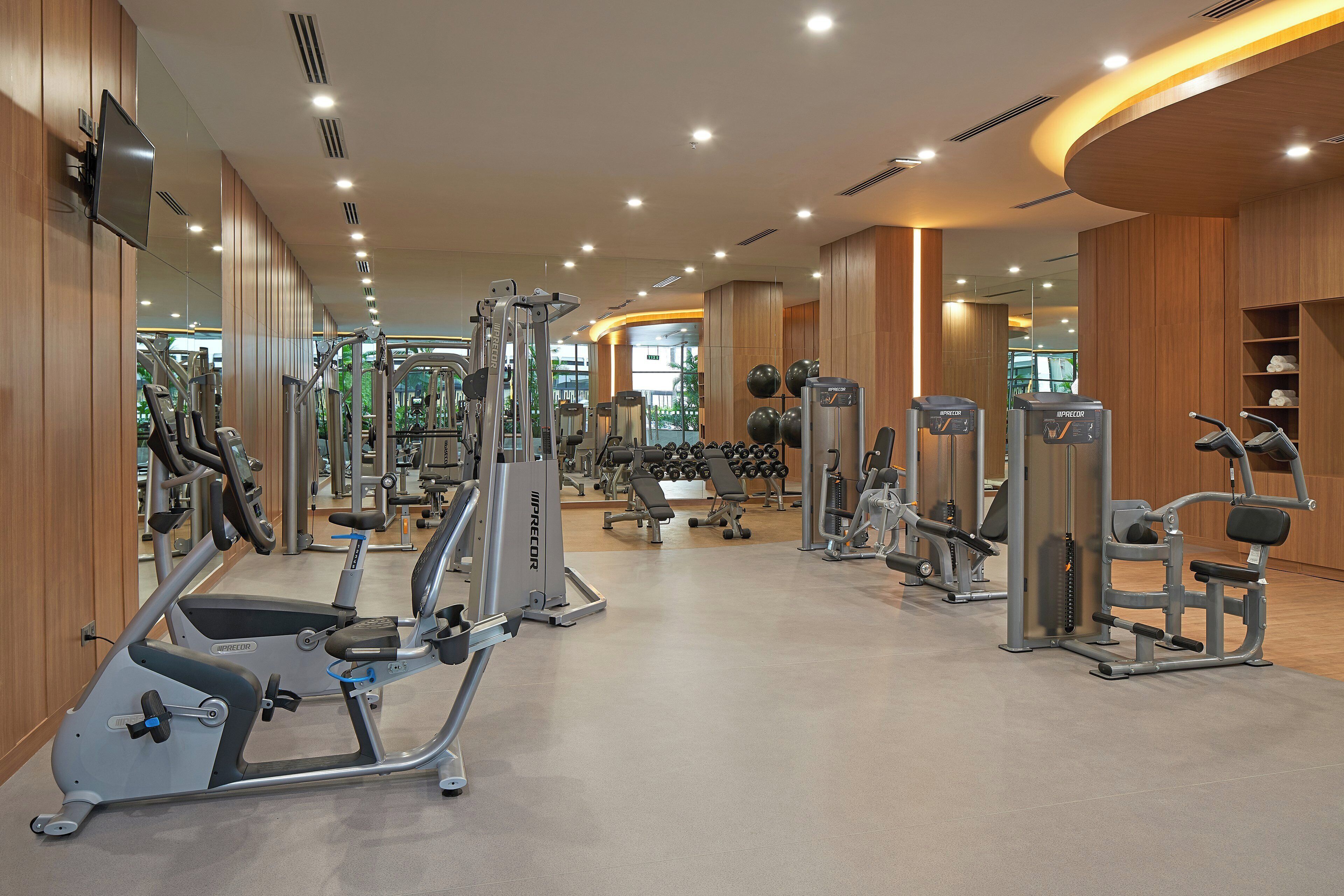 Un gimnasio moderno con diversos equipos de ejercicio, espejos y un interior bien iluminado.