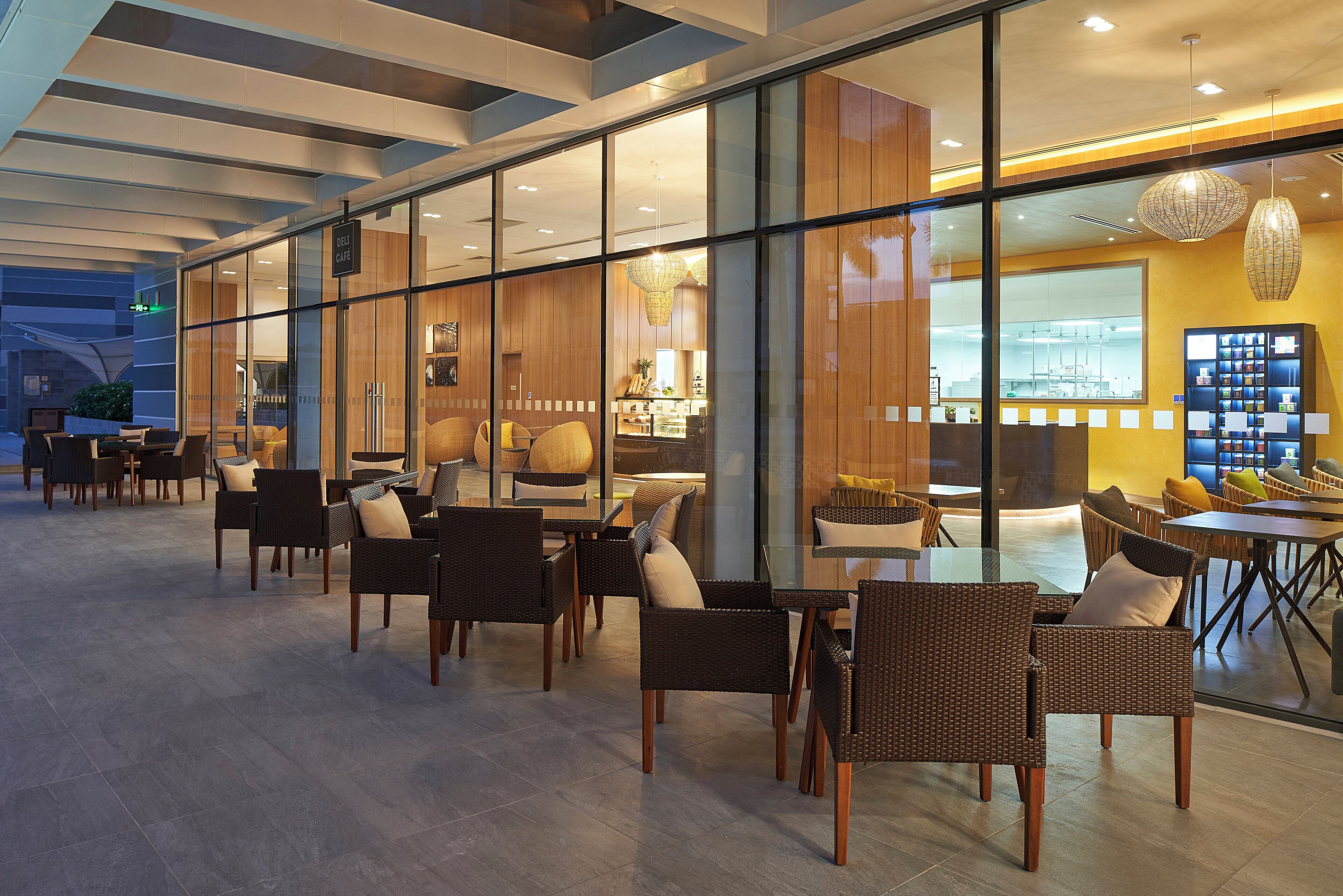 A modern indoor seating area with wicker furniture and glass partitions.