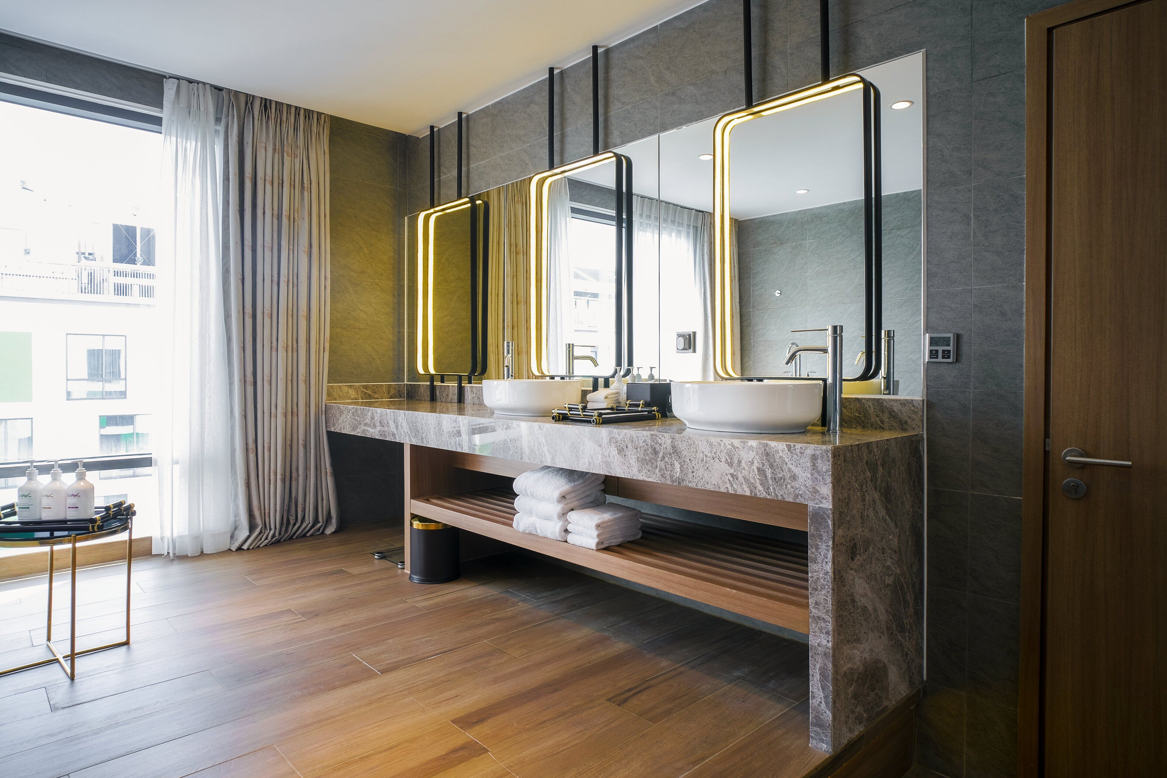 A modern bathroom with two sinks, a large mirror, and a wooden vanity.