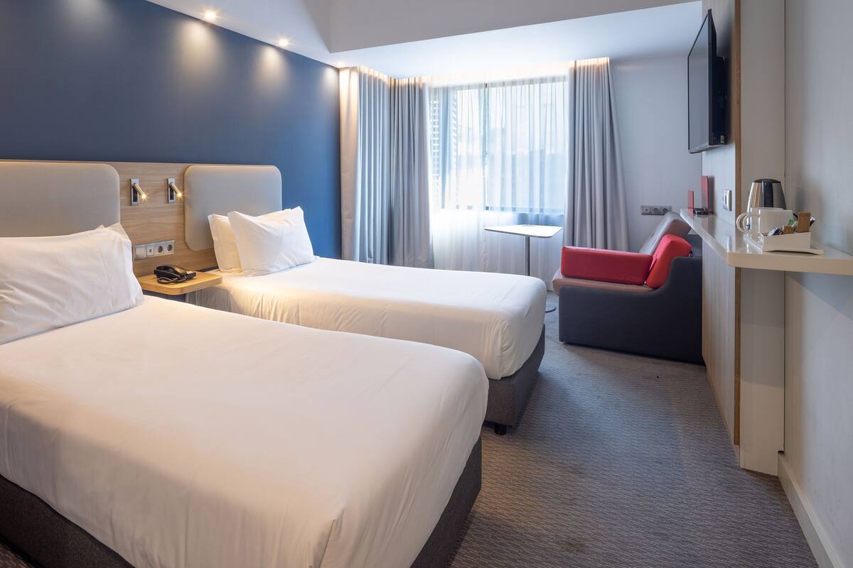 Hotellihuone, jossa on kaksi sänkyä, työpöytä, tuoli ja televisio.