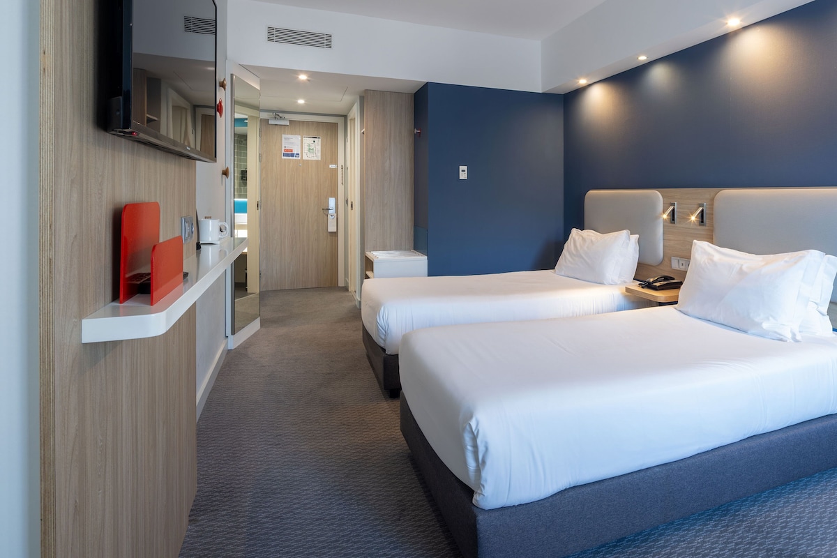 Une chambre d’hôtel avec deux lits, un bureau, une télévision et une salle de bain.