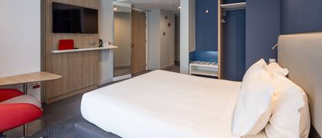 Une chambre d’hôtel moderne dotée d’un grand lit, d’un bureau avec une chaise, d’un téléviseur fixé au mur et d’une armoire.