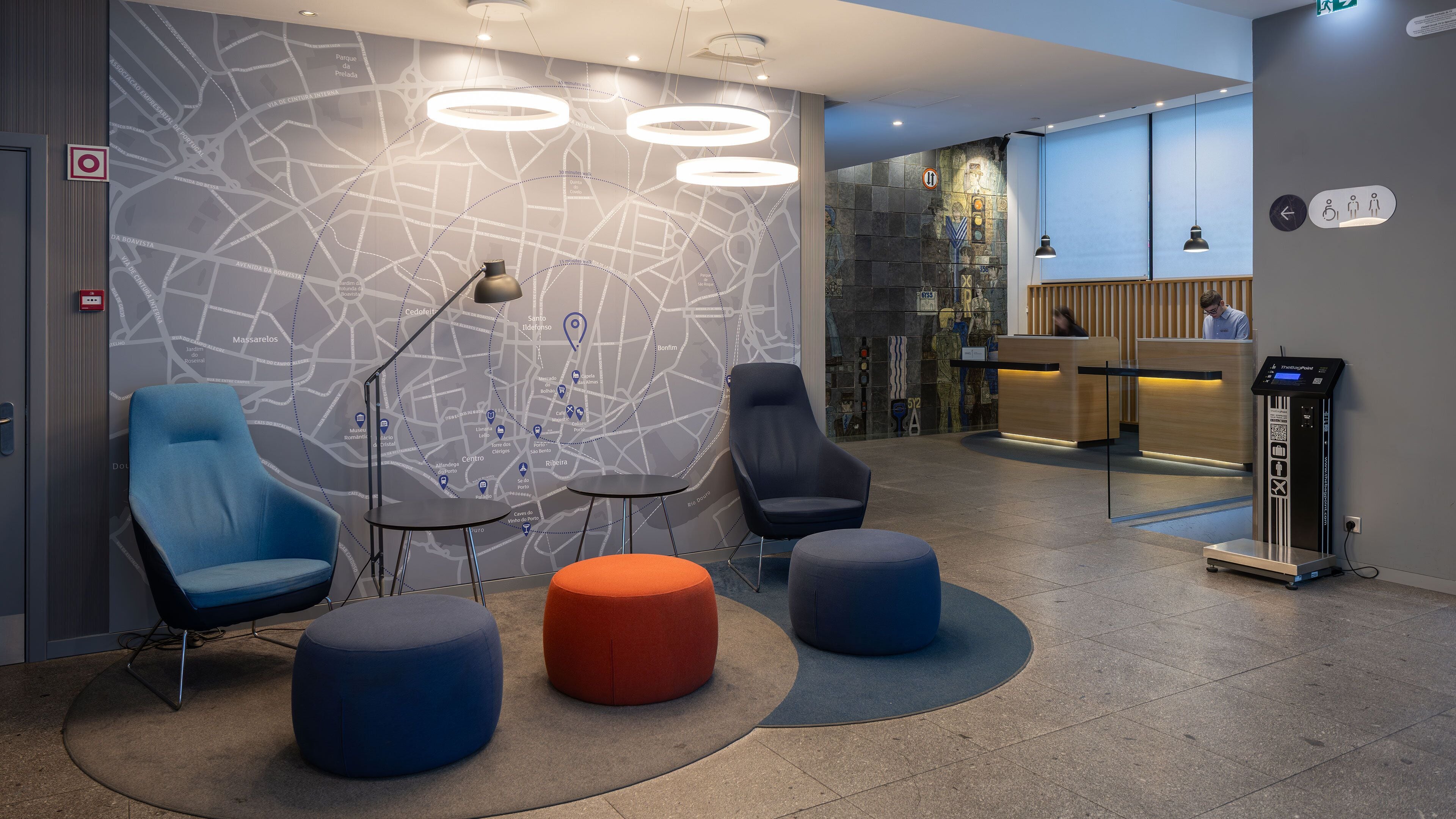 En modern entréhall med en väggkarta, sittgrupp, receptionsdisk och en självbetjäningskiosk.