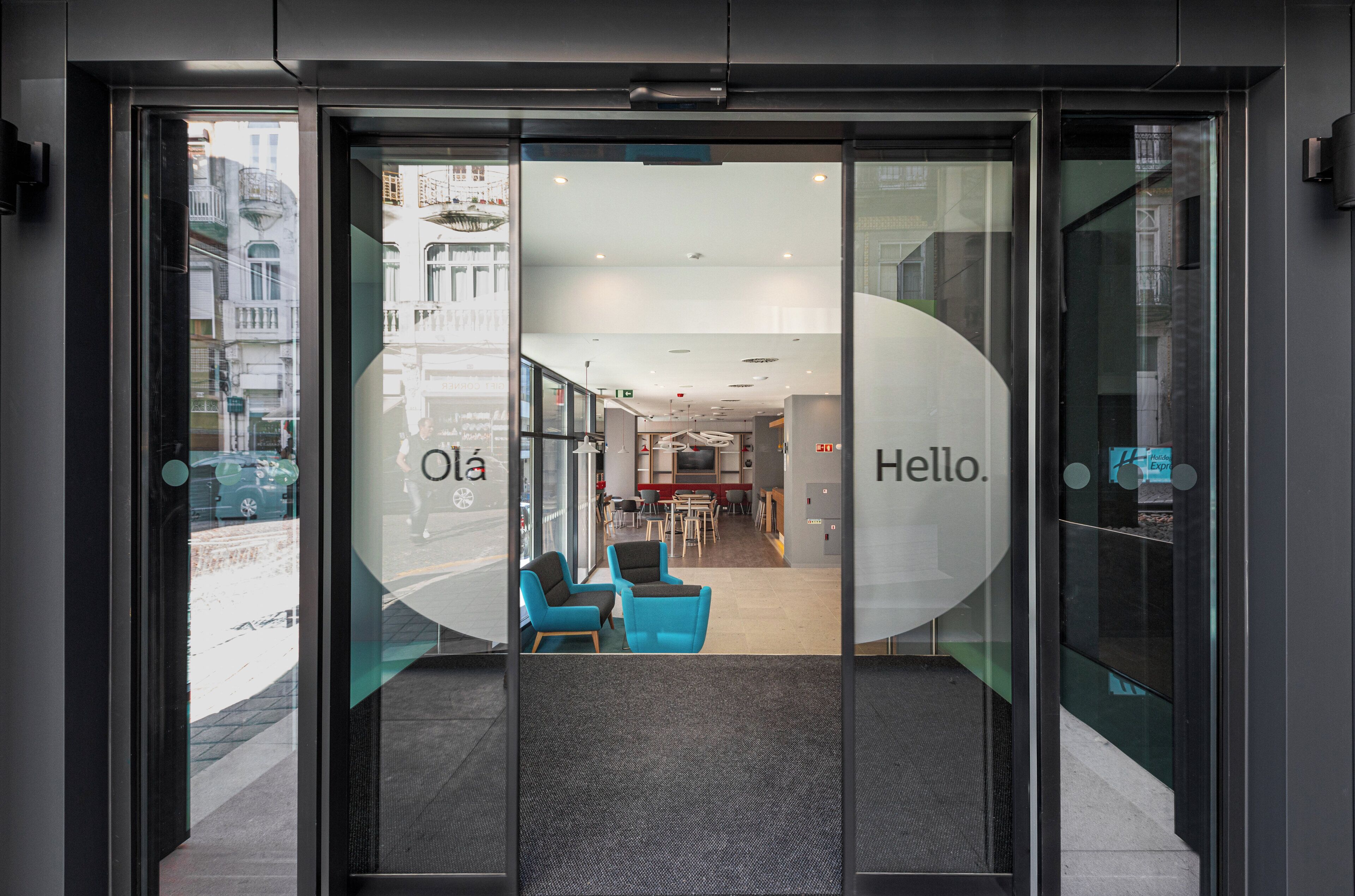 L’entrée d’un hôtel, avec une porte en verre, un comptoir d’accueil et un espace salon visible à l’intérieur.