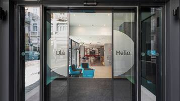 L’entrée d’un hôtel, avec une porte en verre, un comptoir d’accueil et un espace salon visible à l’intérieur.