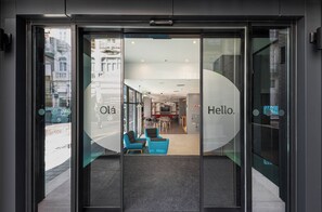 A hotel entrance with a glass door, a reception desk, and seating area visible inside. - Holiday Inn Express Porto City Center by IHG (Porto)