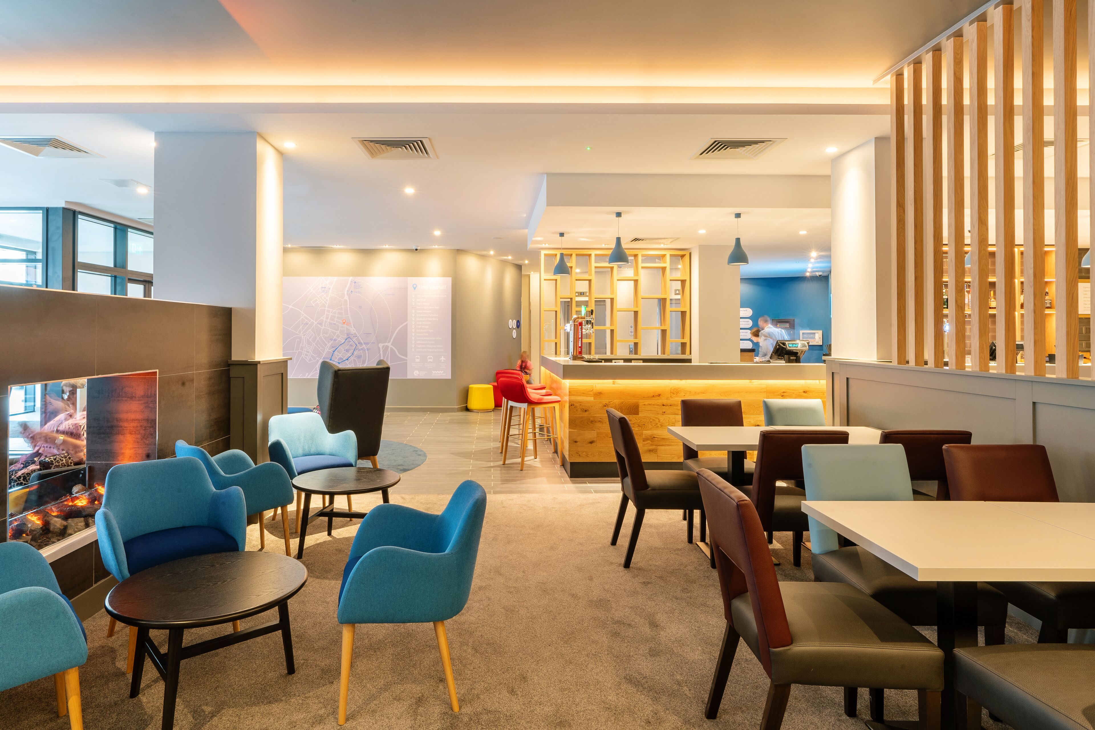 A modern hotel lobby with seating areas, a reception desk, and a bar.