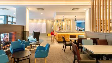 Un moderno vestíbulo de hotel con zonas de estar, un mostrador de recepción y un bar.