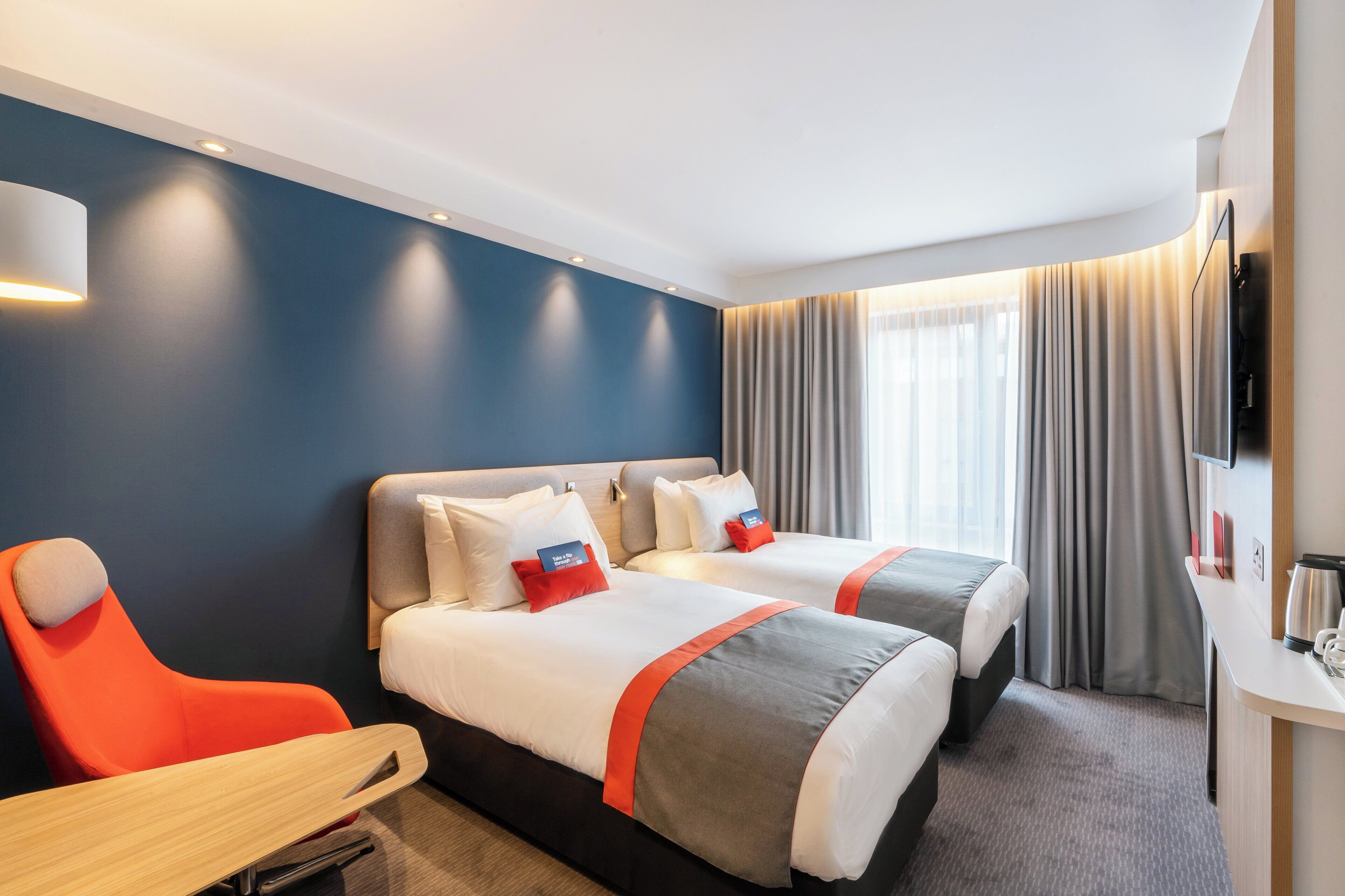 Une chambre d’hôtel avec deux lits, un bureau et une télévision.