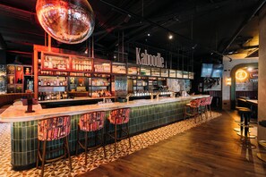 A bar area with a counter, stools, shelves with bottles, and a disco ball. - Holiday Inn Express Derry - Londonderry by IHG (Londonderry)