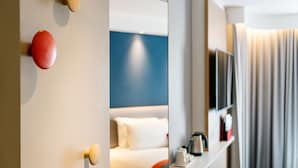 A hotel room with a bed, a TV, and a mirror.