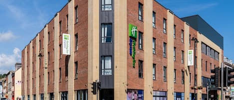 Un hotel de varios pisos con fachada de ladrillo, ventanas grandes y señalización de Holiday Inn Express.